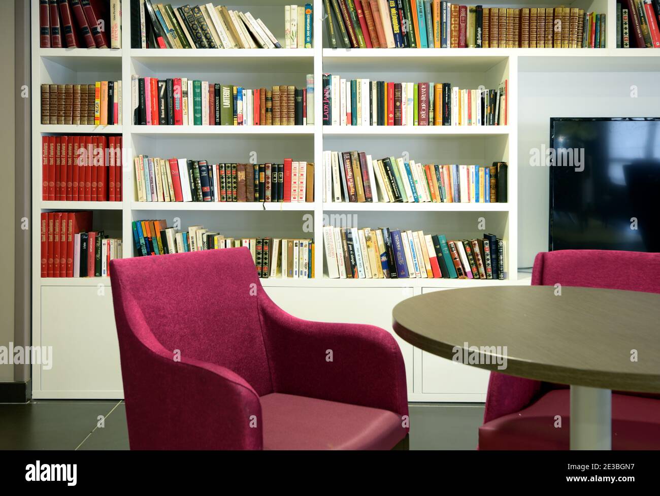 Moderne oder zeitgenössische weiße Bücherregale oder Bücherregale und Bücher in Moderne Einrichtung mit Tisch und Stühlen, Sitzbereich Stockfoto