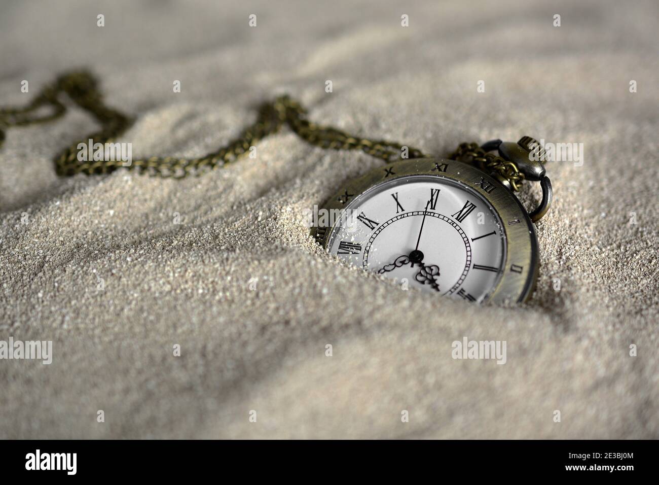 Alte Taschenuhr halb im Sand vergraben. Alte Taschenuhr im Sand verloren Stockfoto