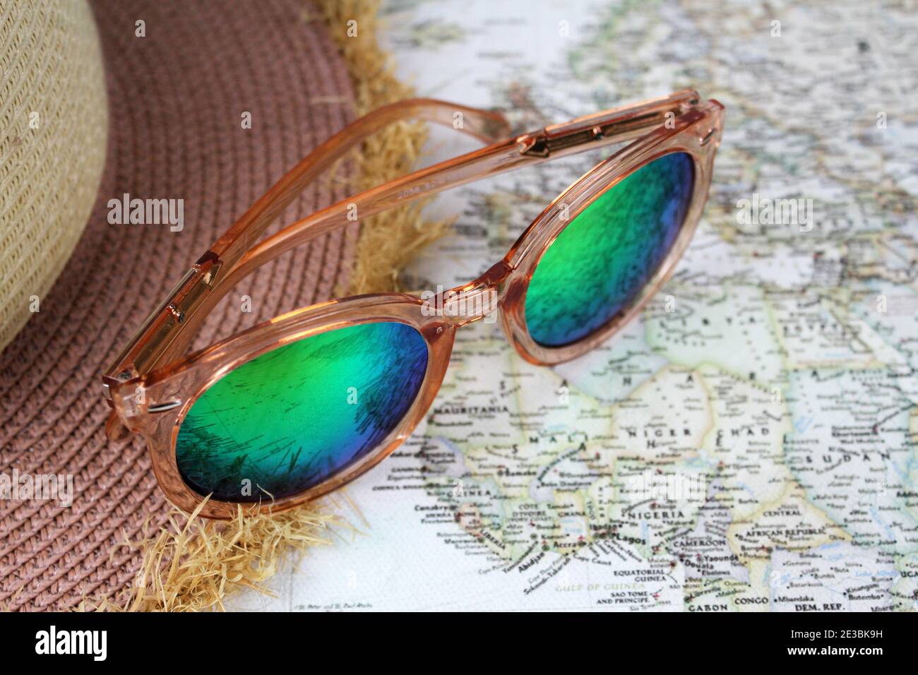 Eine funky Sonnenbrille neben einem Strohhut auf einer Weltkarte. Stockfoto