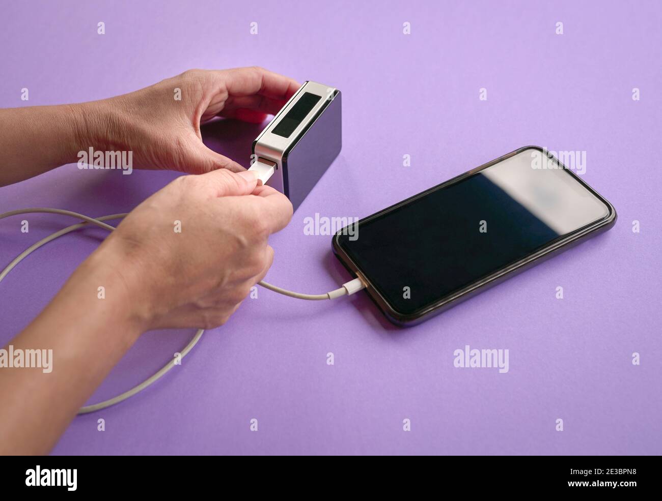 Frau lädt Handy mit einer Powerbank. Nahaufnahme. Stockfoto