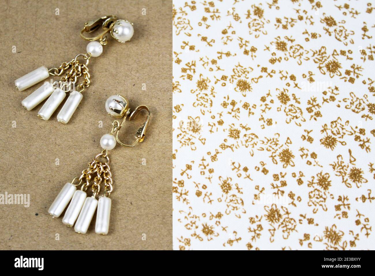 Ein Paar Ohrringe aus Gold und Perlen vor einem floralen Hintergrund. Stockfoto