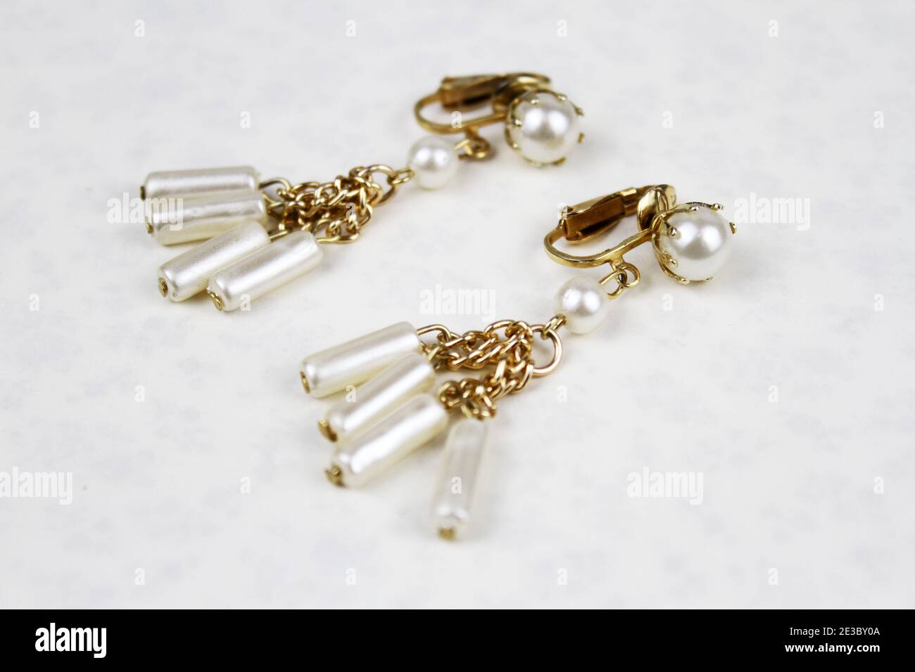 Ein Paar Ohrringe aus Gold und Perlen vor einem weißen Hintergrund. Stockfoto
