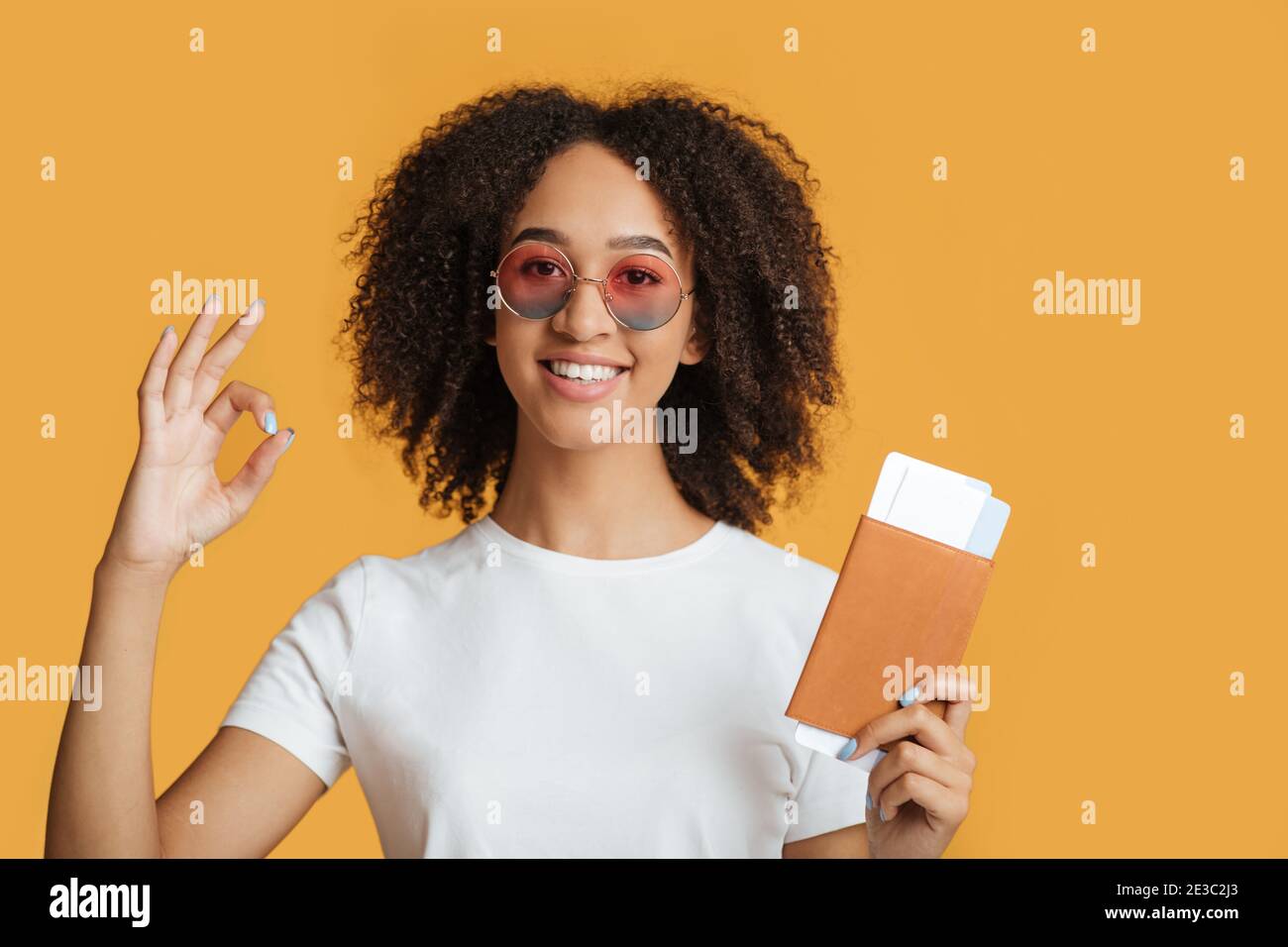Flug und Reise nach Lockdown covid-19. Glückliche junge gemischte Rennen Frau in Mode Brille halten Pass und Ticket Stockfoto