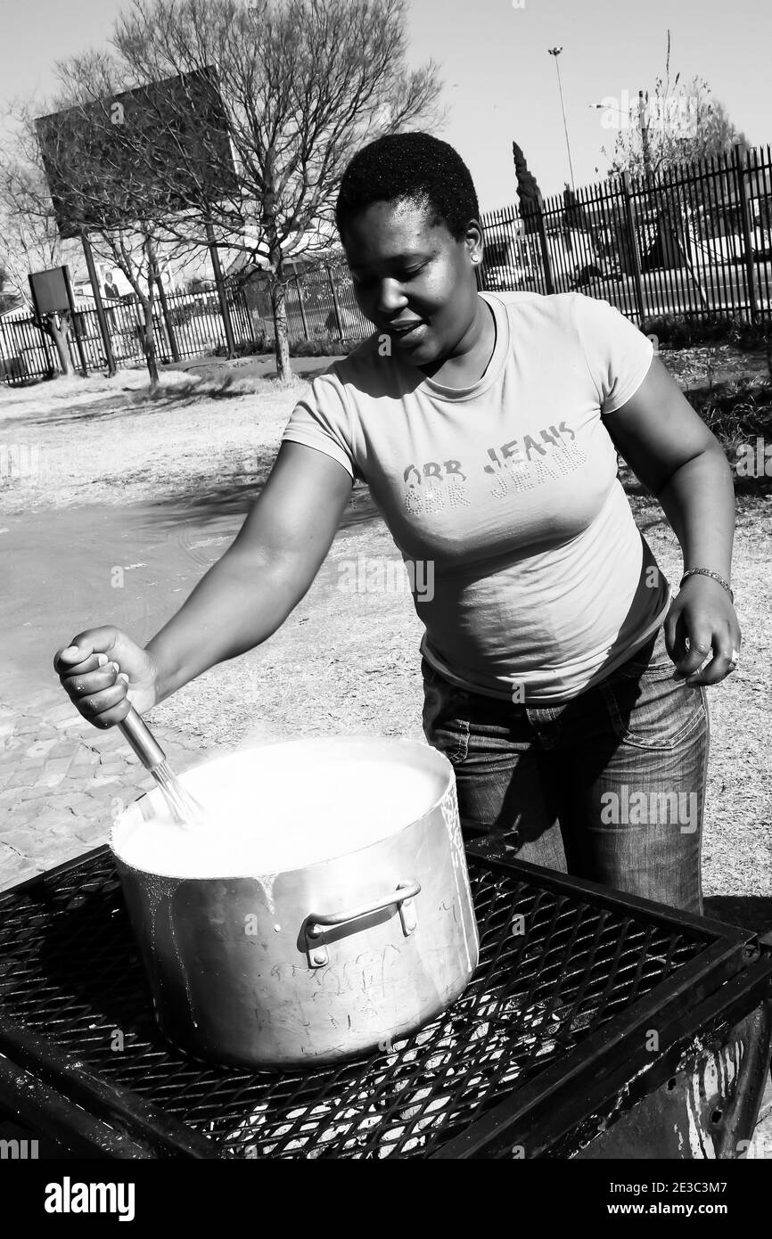 JOHANNESBURG, SÜDAFRIKA - 05. Jan 2021: Soweto, Südafrika - 21. Juli 2012: Afrikanerin kocht Mielie Pap Maisbrei in der Seitenstraße in urb Stockfoto