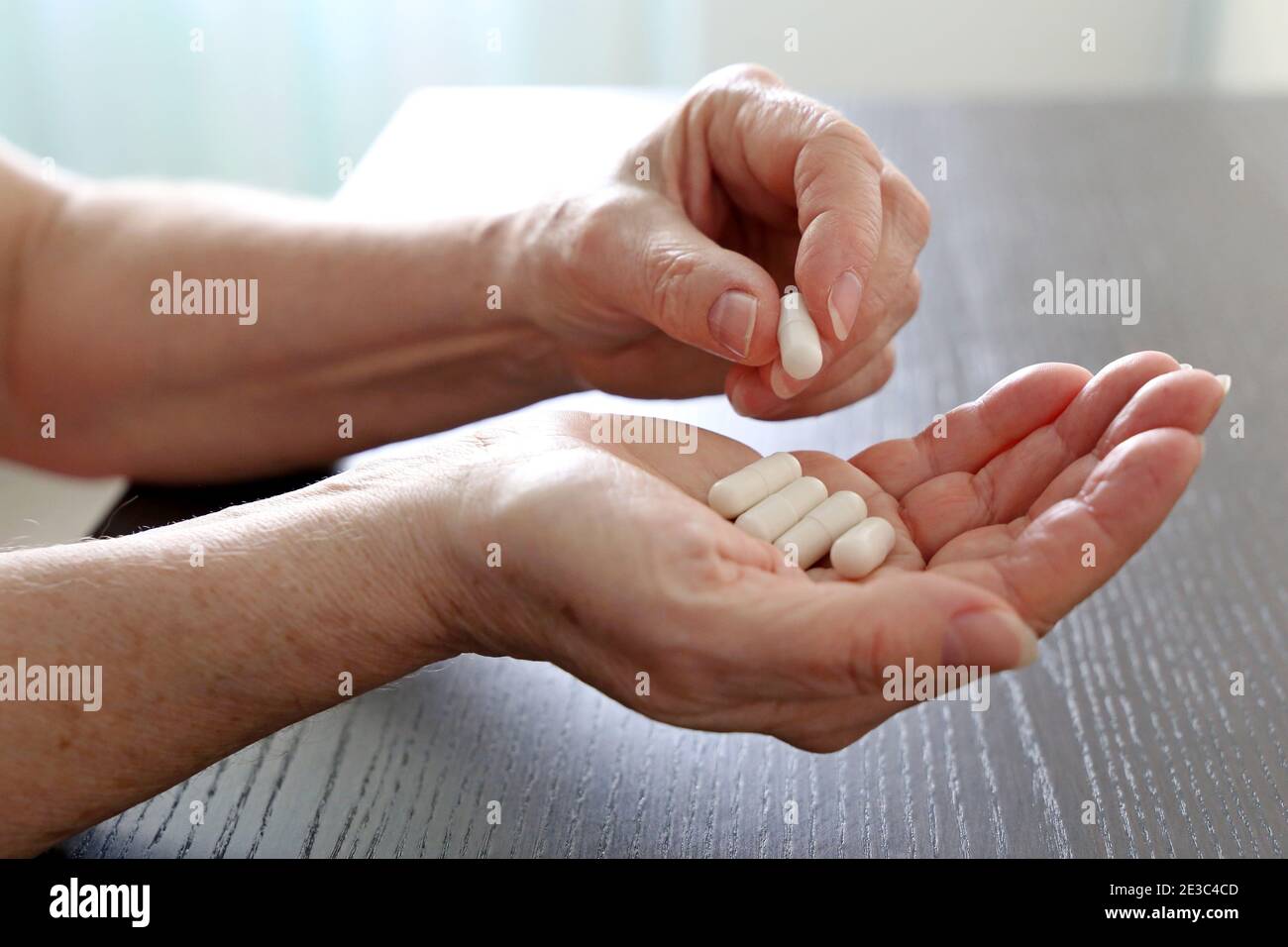 Ältere Frau mit Pillen in faltigen Händen. Medikamente in Kapseln, Einnahme von Beruhigungsmitteln oder Vitaminen Stockfoto