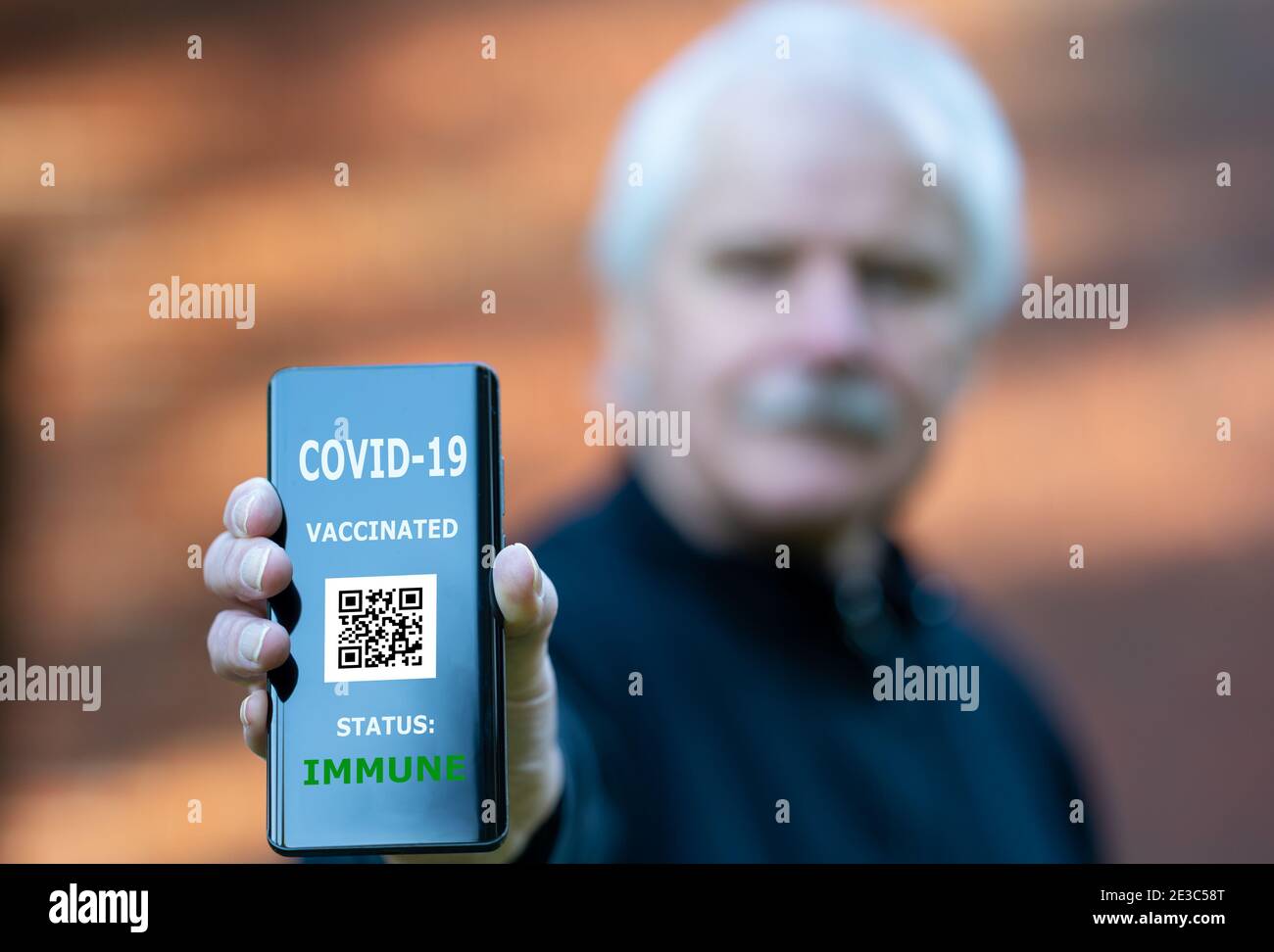 Älterer Mann, der einen Impfpass auf einem Mobiltelefon vorweist, der auf eine Impfung gegen covid-19 hinweist. Stockfoto