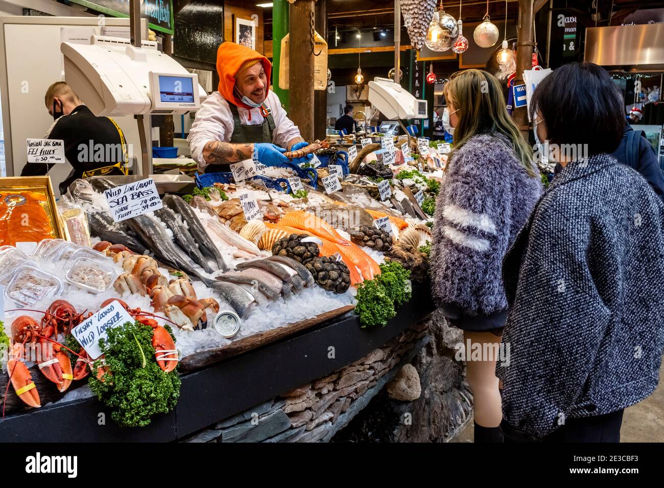 Junge asiatische Frauen kaufen Meeresfrüchte im Borough Market, London, Großbritannien. Stockfoto