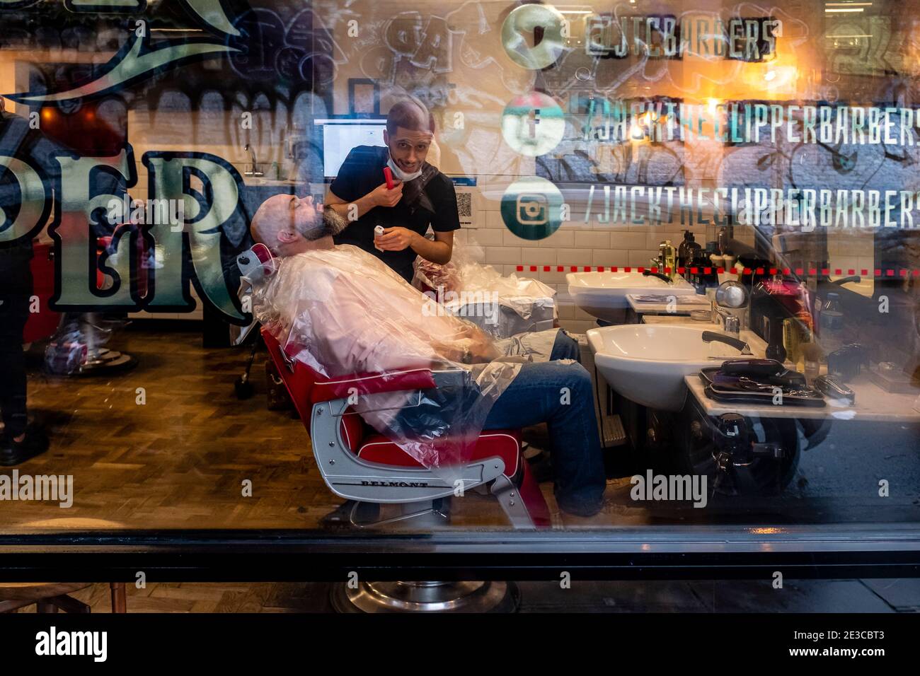 A man has A Beard and Moustache Trim in A Barber Shop in Brick Lane, London, UK. Stockfoto