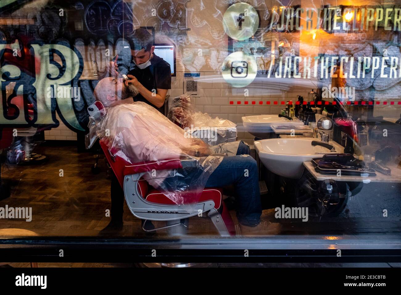 A man has A Beard and Moustache Trim in A Barber Shop in Brick Lane, London, UK. Stockfoto
