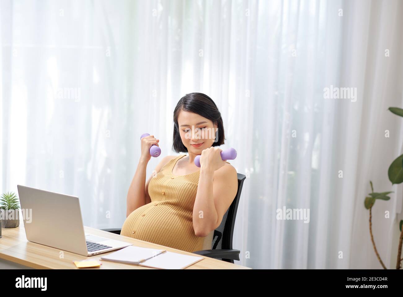 Glückliche schwangere Frau im Büro aktiv Stockfoto