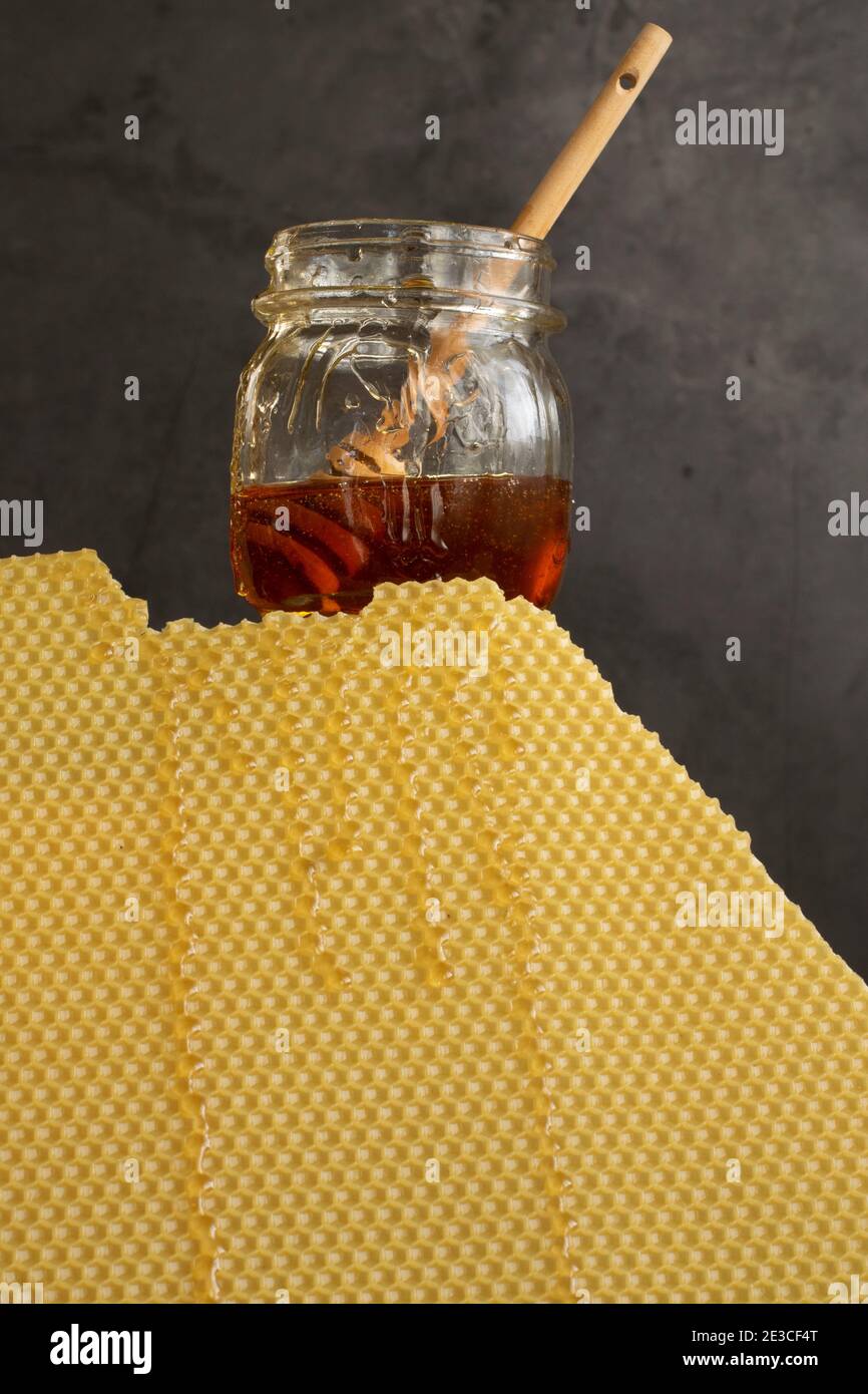 Glas mit rohem Honig und Bienenwabe auf dunklem Hintergrund, gesundes Ernährungskonzept Stockfoto