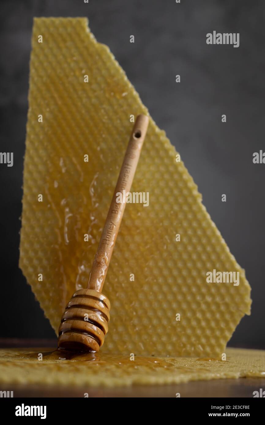 Löffel mit rohem Honig und Bienenwabe auf dunklem Hintergrund, gesundes Ernährungskonzept Stockfoto