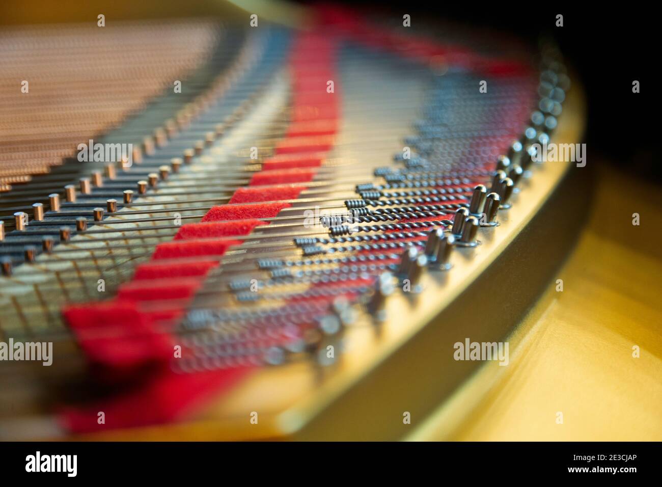 Der farbenfrohe Teil des Resonanzboden eines deutschen Steinway M Klaviers. Licht ist Sonnenlicht durch ein nahe gelegenes Fenster. Stockfoto