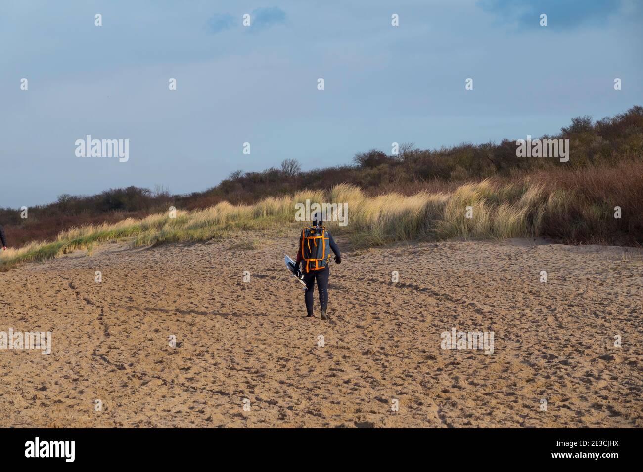 Oostvoorne:Holland,17-jan-2021:Frau mit Wellenbrett am Strand von oostvoorne spazieren, ist dies eine beliebte Palce für Wassersport Stockfoto