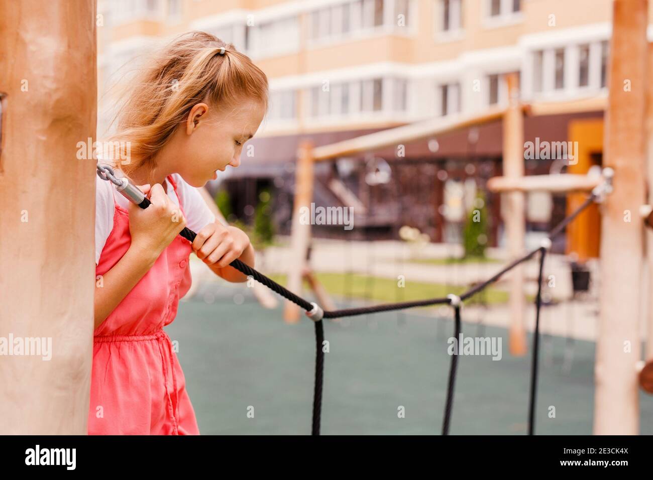 Ein Teenager Mädchen in einem Sommerkleid spielt auf dem Spielplatz in der Nähe ihres Hauses. Stockfoto