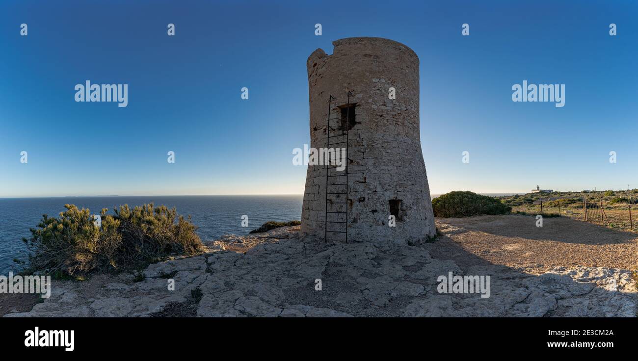 Bild des Cap Blanc Wachturms auf Mallorca mit dem Leuchtturm im Hintergrund bei Sonnenuntergang.dieser Turm wurde in den XVI warnte vor Piratenangriffen. Stockfoto