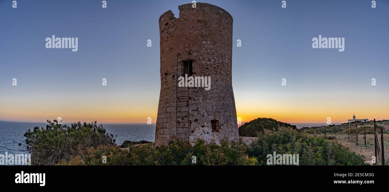 Bild des Cap Blanc Wachturms auf Mallorca mit dem Leuchtturm im Hintergrund bei Sonnenuntergang.dieser Turm wurde in den XVI warnte vor Piratenangriffen. Stockfoto