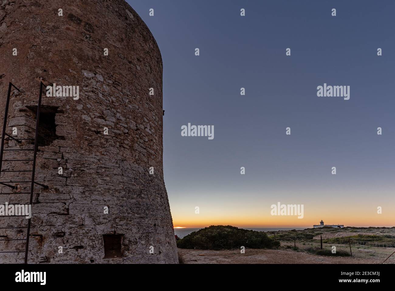 Bild des Cap Blanc Wachturms auf Mallorca mit dem Leuchtturm im Hintergrund bei Sonnenuntergang.dieser Turm wurde in den XVI warnte vor Piratenangriffen. Stockfoto