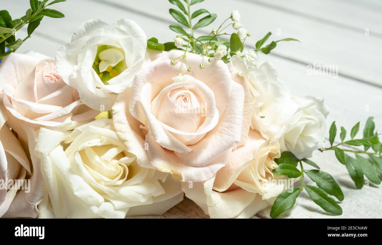 Blumenzusammensetzung von hellen Rosen und eustoma auf dem Hintergrund eines hölzernen weißen Tisches. Hochzeitstag Grußkarte. Stockfoto