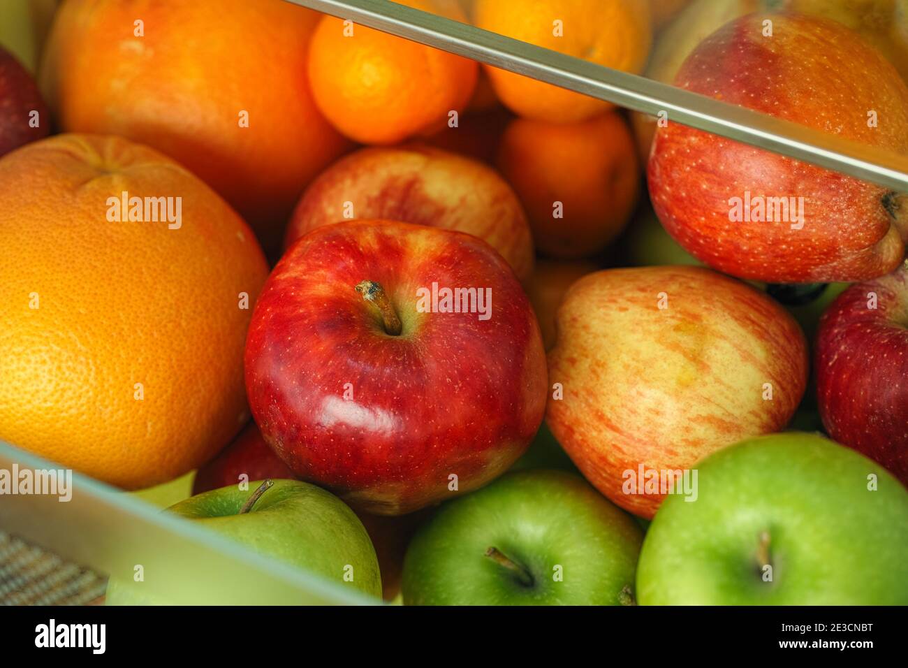 Bio-Äpfel und Zitrusfrüchte in einem Behälter aus dem Kühlschrank. Nahaufnahme. Stockfoto