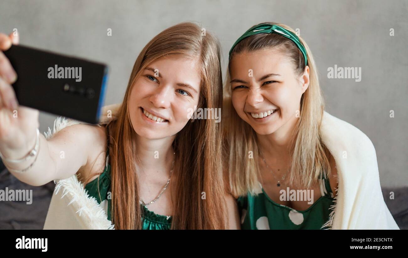 Zwei schöne glückliche Freundinnen, die Selfie mit dem Smartphone bei Pyjama machen Party Stockfoto