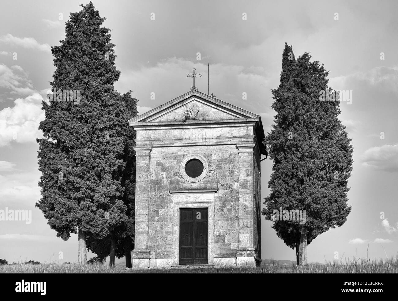 Alte Kirche von Vitaleta mit Bäumen auf beiden Seiten in San Quirico d'Orcia, in der Nähe von Pienza, Toskana, Italien im Mai - Kapelle der Madonna di Vitaleta Stockfoto