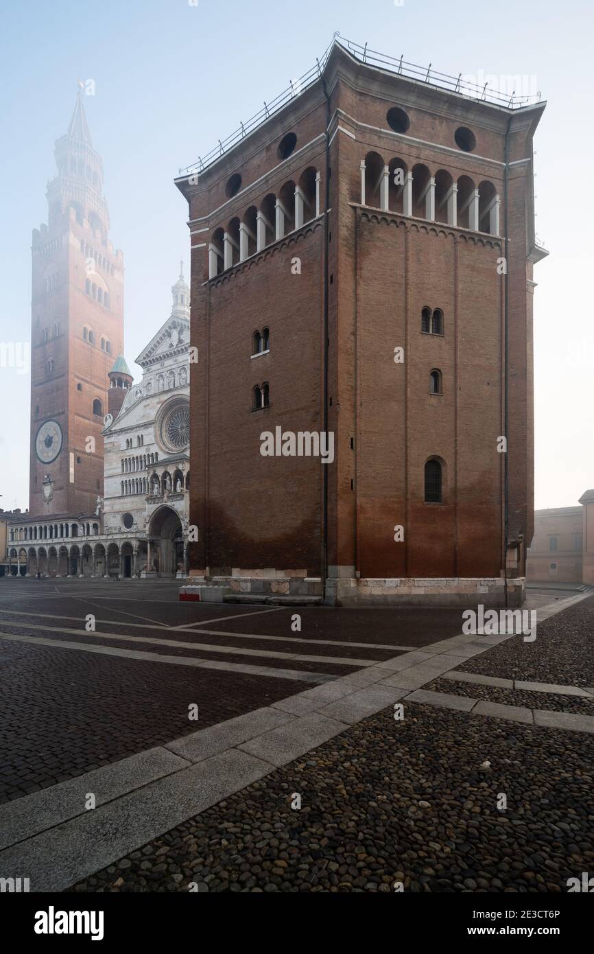 Die romanische Taufkapelle aus dem 12. Jahrhundert in Cremona, Italien, mit der mittelalterlichen Kathedrale und dem Glockenturm von Torrazzo im Hintergrund an einem nebligen Tag Stockfoto