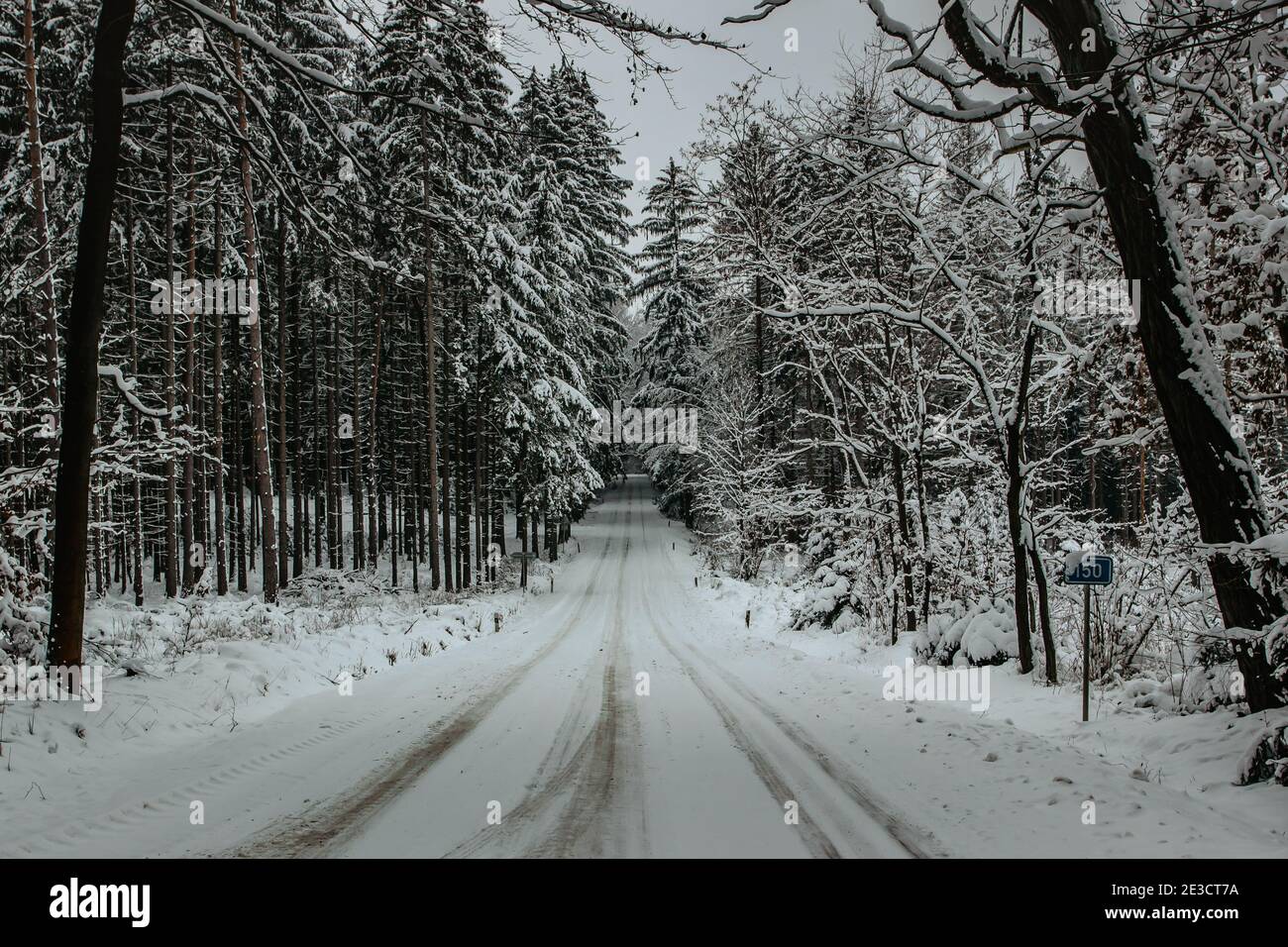 Gefährliche Strecke der Straße mit Schnee und Eis bedeckt.Snowy Straße Durch Wald.Winterpanorama.Fahren in eisiger gefrorener Landschaft.Schlechtes Wetter.S Stockfoto