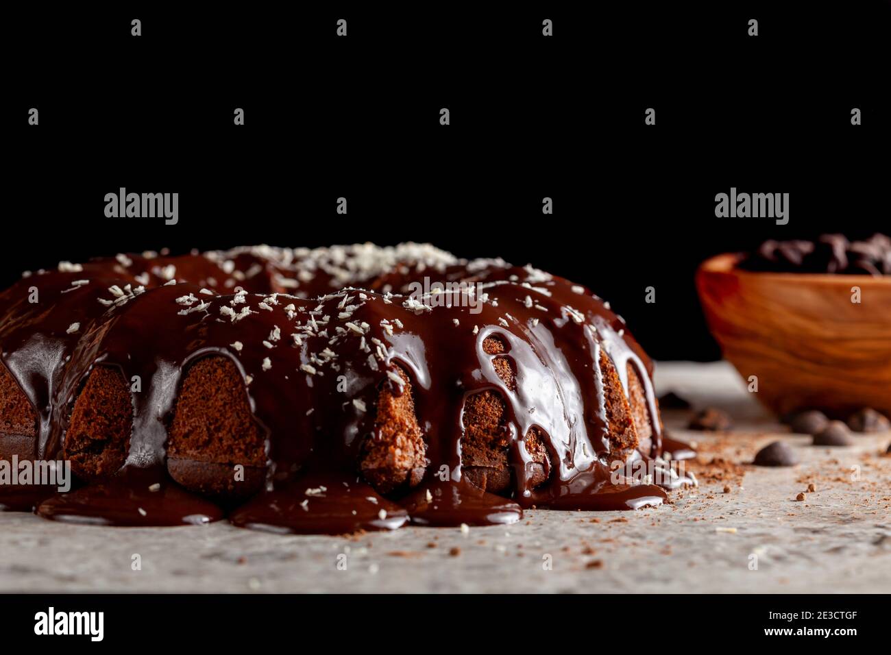 Seitenansicht eines runden Schokoladenkuchens mit geschmolzenem Pudding-Eis und Schokoladenstückchen in einer Schüssel im Hintergrund. Die Dekoration dieser leckeren Torte Stockfoto