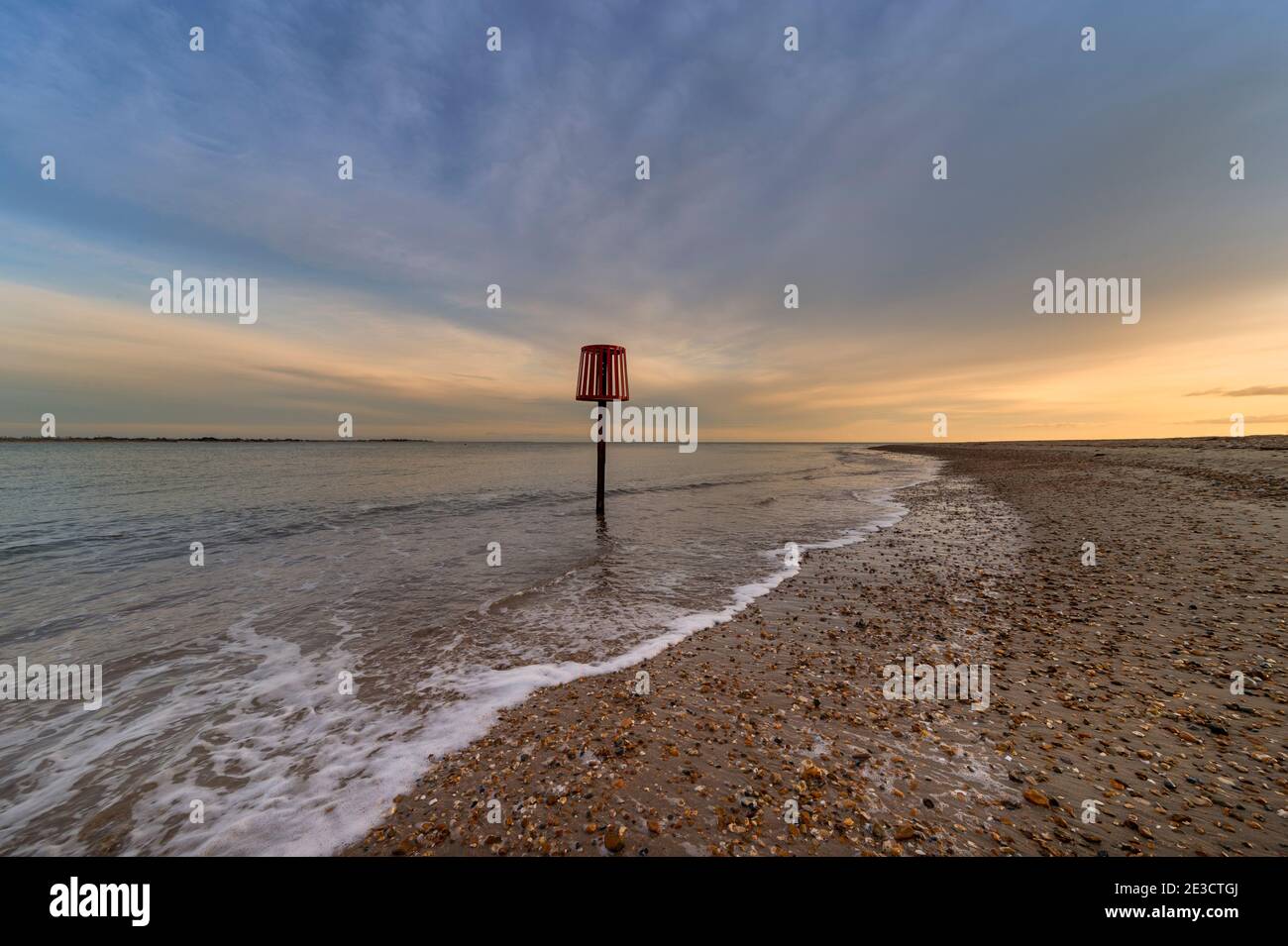 Leerer Kiesstrand auf Hayling Island. Abenddämmerung mit roter Navigationsmarkierung. Stockfoto