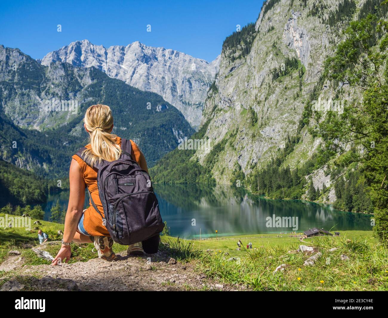 Kaukasische Frau sitzt auf Felsen mit Blick auf See im Tal Stockfoto