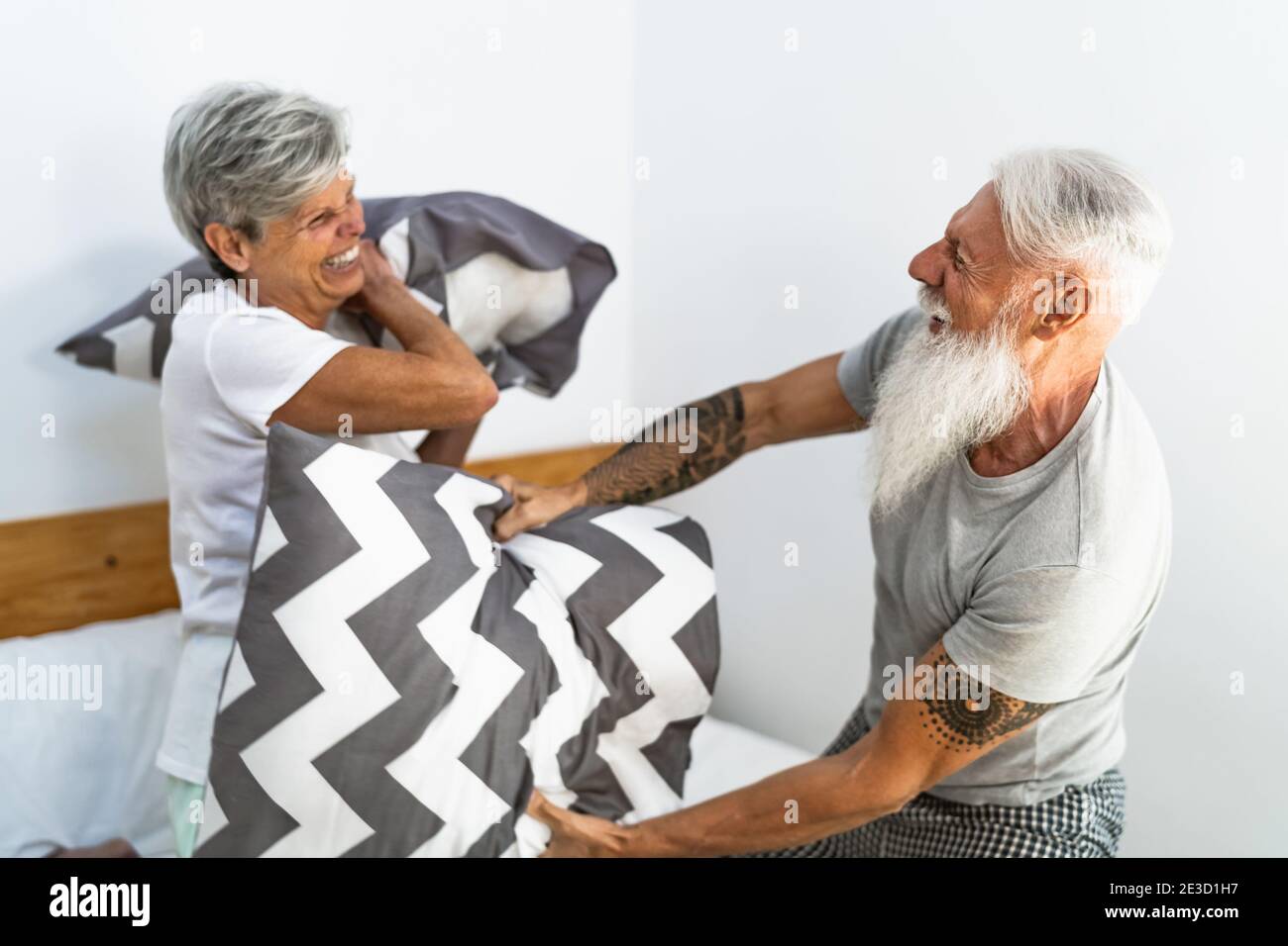 Glückliches Seniorenpaar, das Spaß beim Kämpfen mit Kissen im Bett hatte - Ältere Lebensweise und Liebesbeziehung Konzept Stockfoto