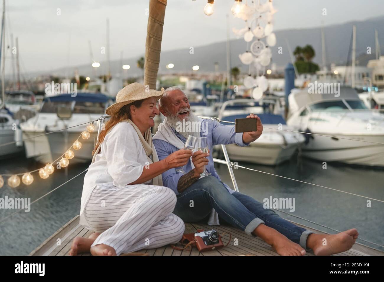 Ein älteres Paar, das während eines Selfies auf einem Segelbooturlaub Champagner toaste - Glückliche reife Menschen Spaß haben Hochzeitstag zu feiern Stockfoto Ein älteres Paar, das während eines Selfies auf einem Segelbooturlaub Champagner toaste - Glückliche reife Menschen Spaß haben Hochzeitstag zu feiern Stockfoto