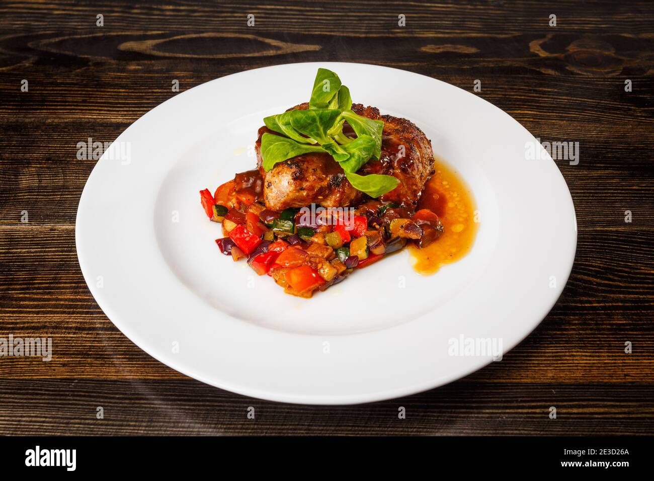 Saftiges Stück Fleisch mit geschmortem Gemüse und Basilikum- und ...