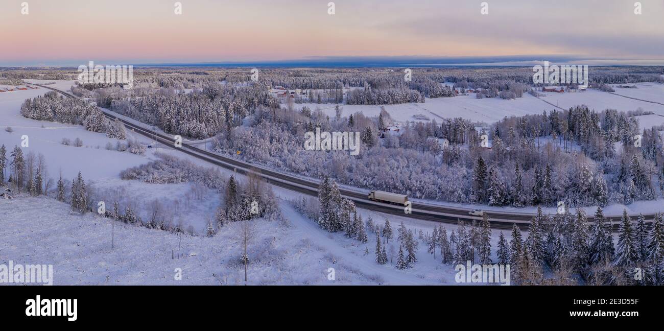 Spektakuläre Winter Luftaufnahme der Europäischen Route E4 in der Nähe von Umea Stadt. Landschaftlich gefrorener skandinavischer Kiefernwald, der von viel Schnee bedeckt ist. Stockfoto