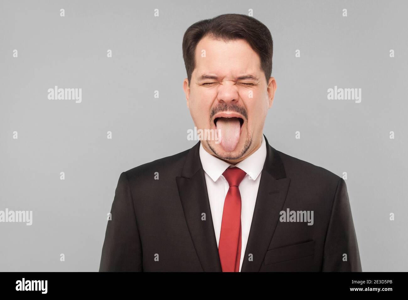 Nahaufnahme Porträt von verrückten Mann in klassischen Anzug, Zunge aus, und brüllen. Indoor-Studio erschossen. Isoliert auf grauem Hintergrund. Schöner Geschäftsmann mit schwarz Stockfoto