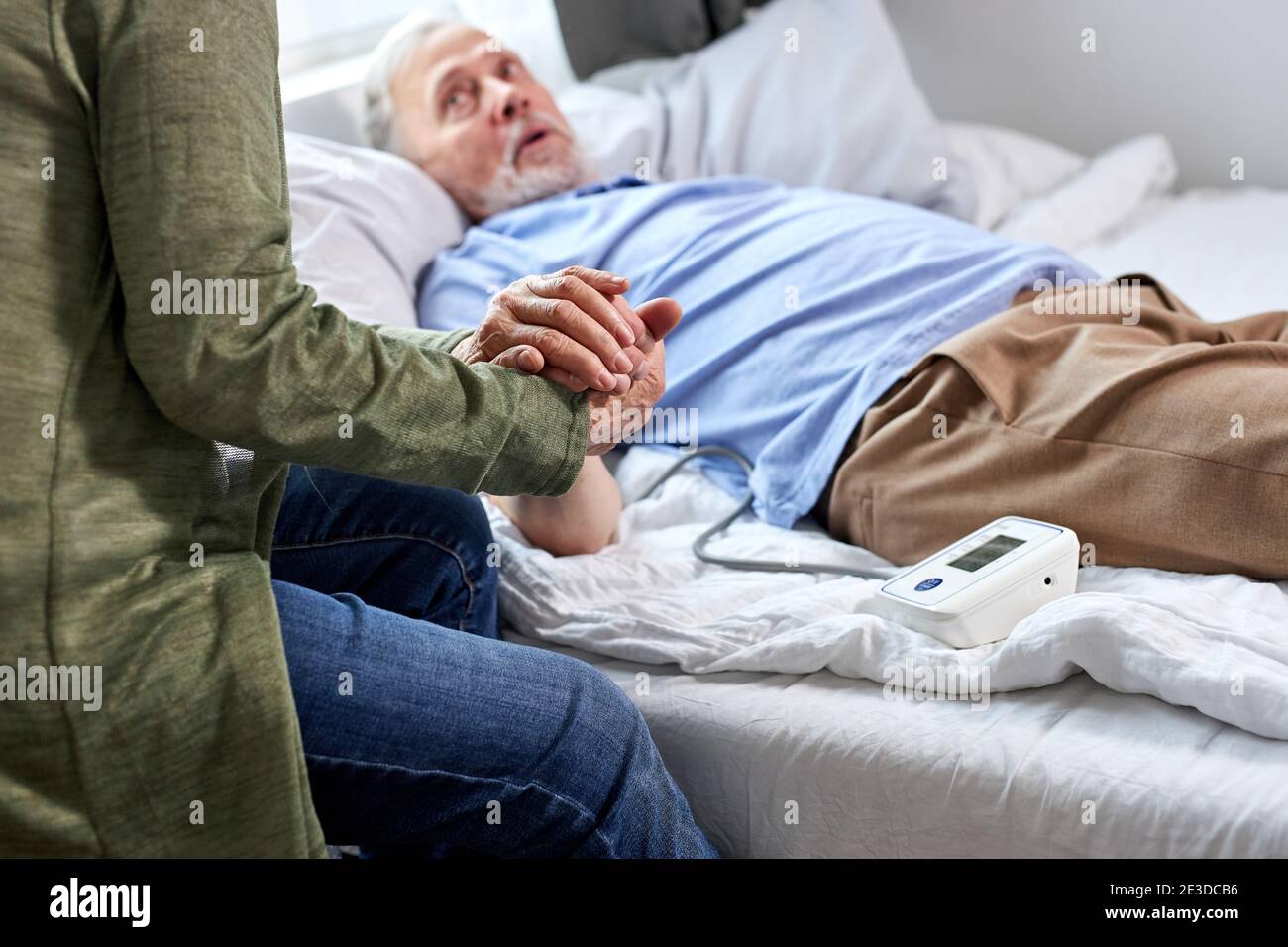 Nahaufnahme eines älteren Paares, das die Hände zusammenhält, unterstützt die Frau ihren kranken Mann, der im Krankenhaus auf dem Bett liegt Stockfoto