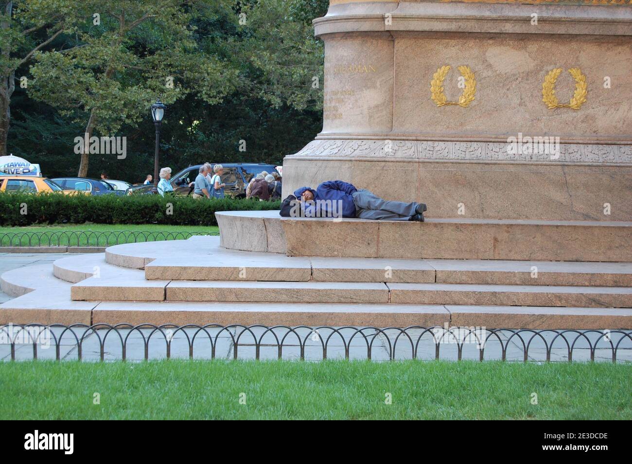 Obdachloser schläft auf der Statue zum Central Park New York USA Tramp New York City schläft vor der Parkstatue Stufen Marmorparks Stockfoto