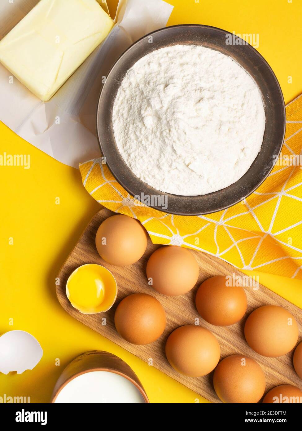 Backzutaten für Kekse, Teig und Gebäck auf gelbem Hintergrund. Mockup für Rezept oder Kochen Blog mit Eiern, Mehl, Butter und Milch. Flach liegend Stockfoto