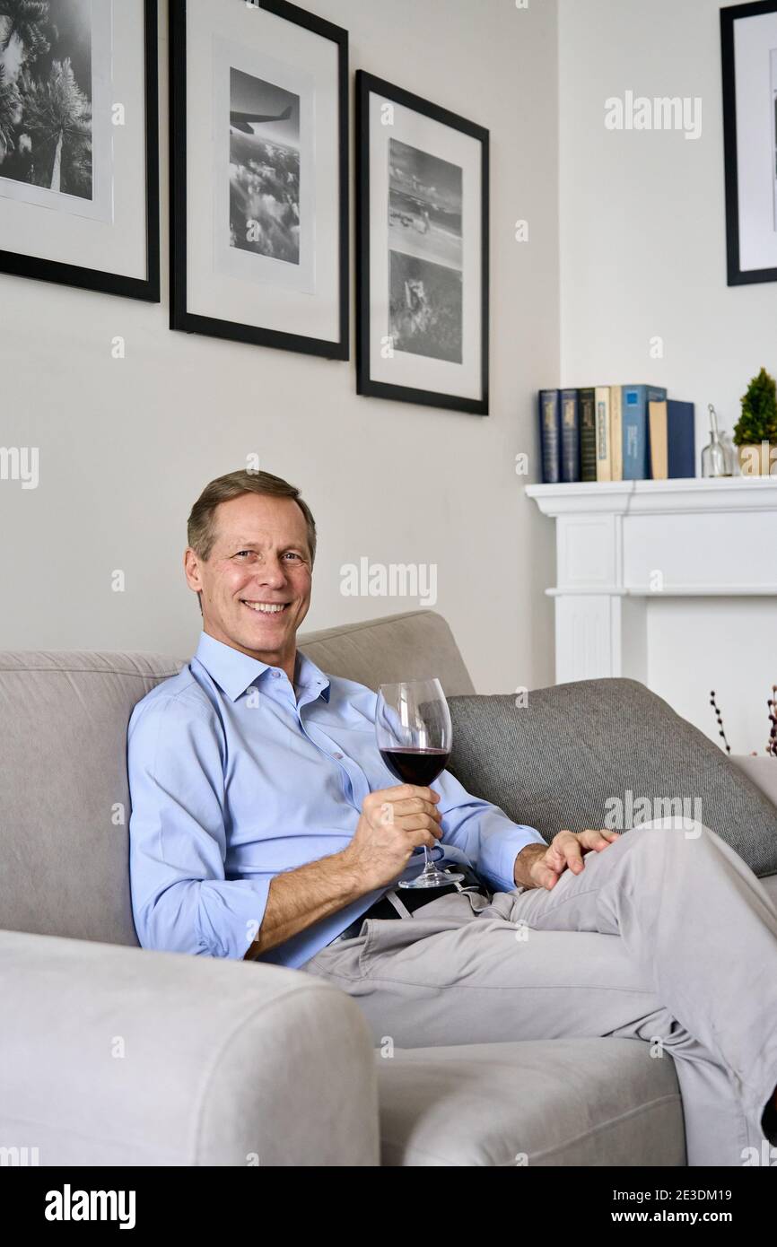 Glücklich heiter reichen alten Senior Single Mann trinken Wein entspannen auf dem Sofa zu Hause. Stockfoto