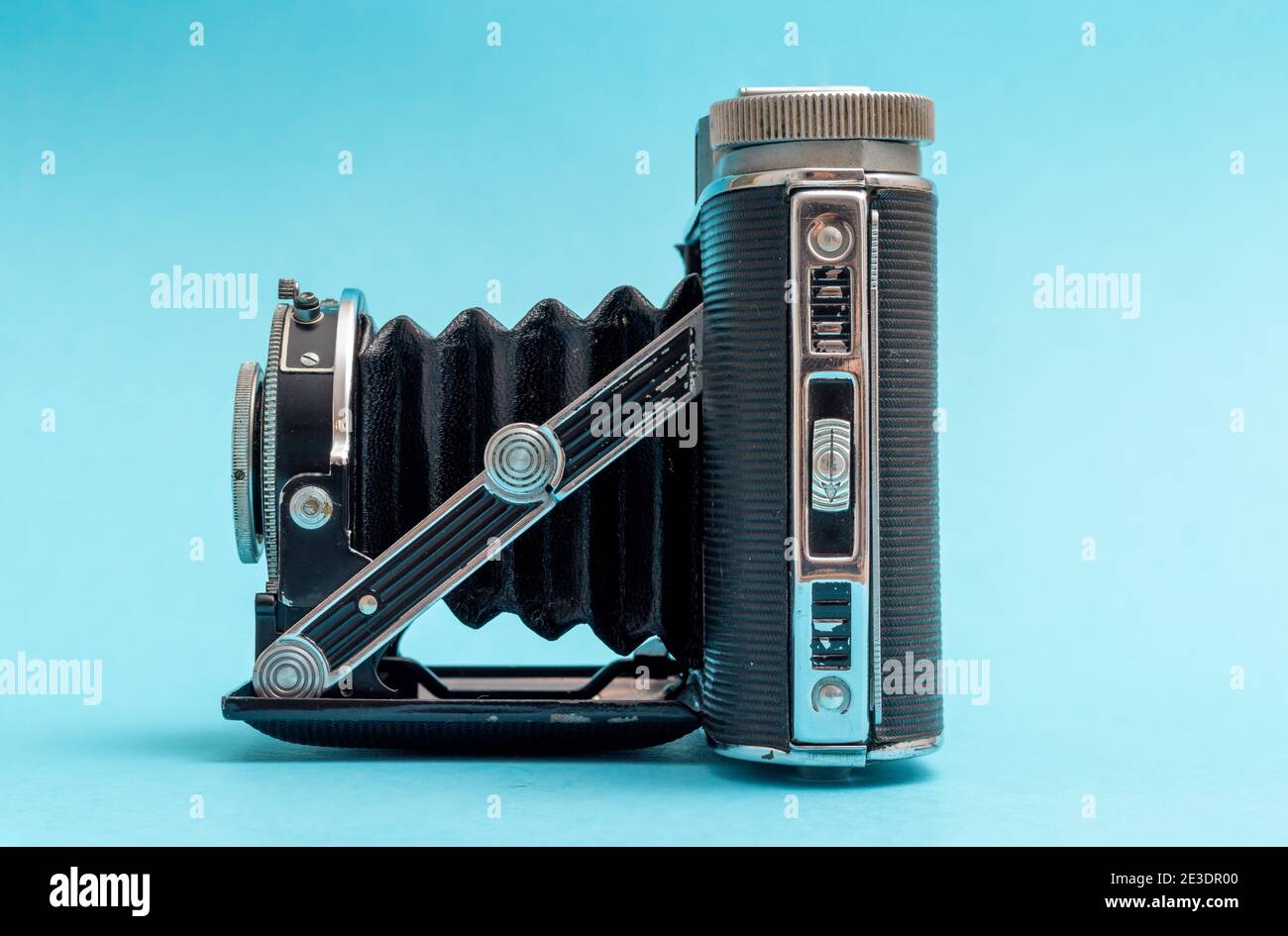 Alte Retro-Kamera von der Seite gegen blaues Pastell mit nostalgischem Gefühl gesehen. Stockfoto