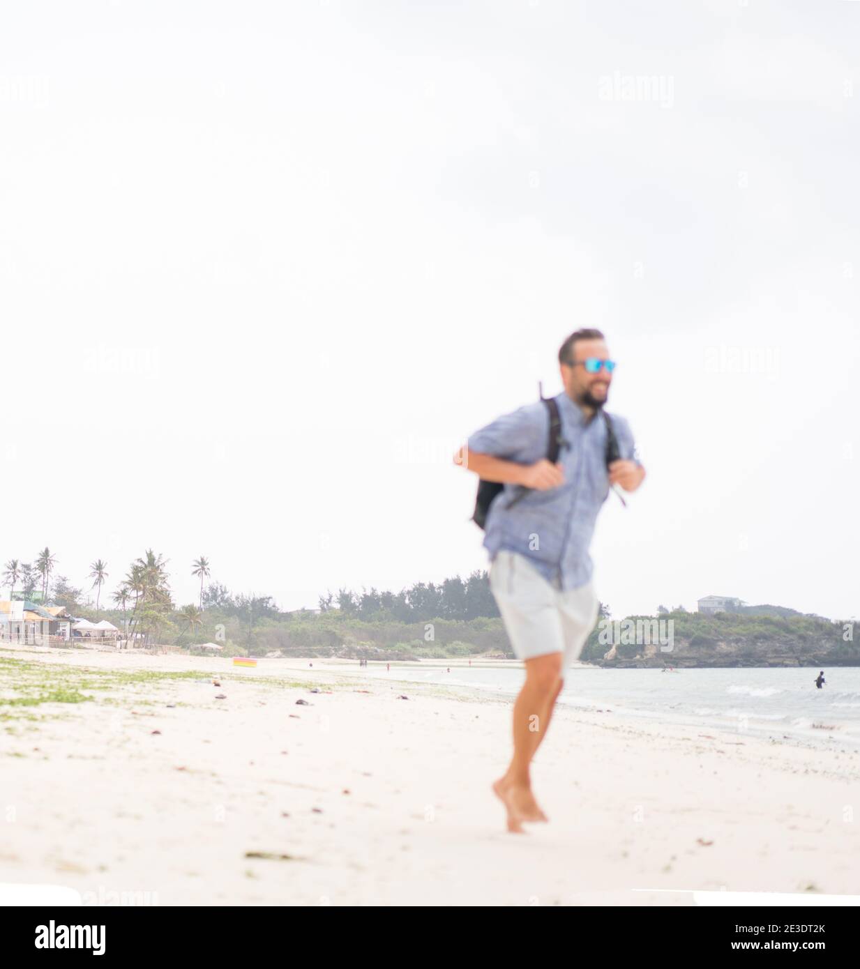 Fröhlicher erwachsener Mann mit Tasche Spaß auf der tropischen Strand Stockfoto