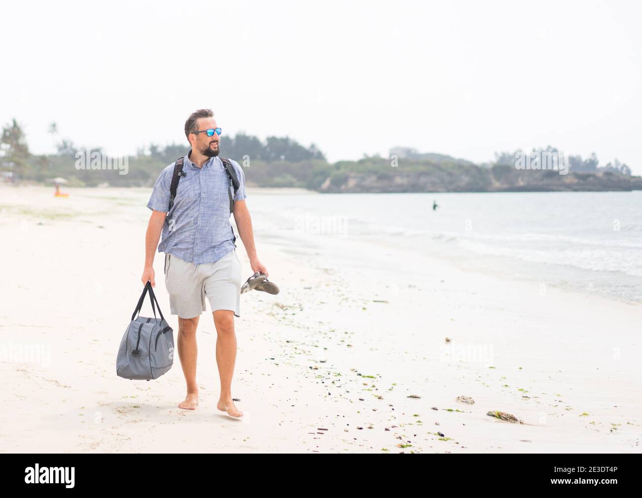 Fröhlicher erwachsener Mann mit Tasche Spaß auf der tropischen Strand Stockfoto