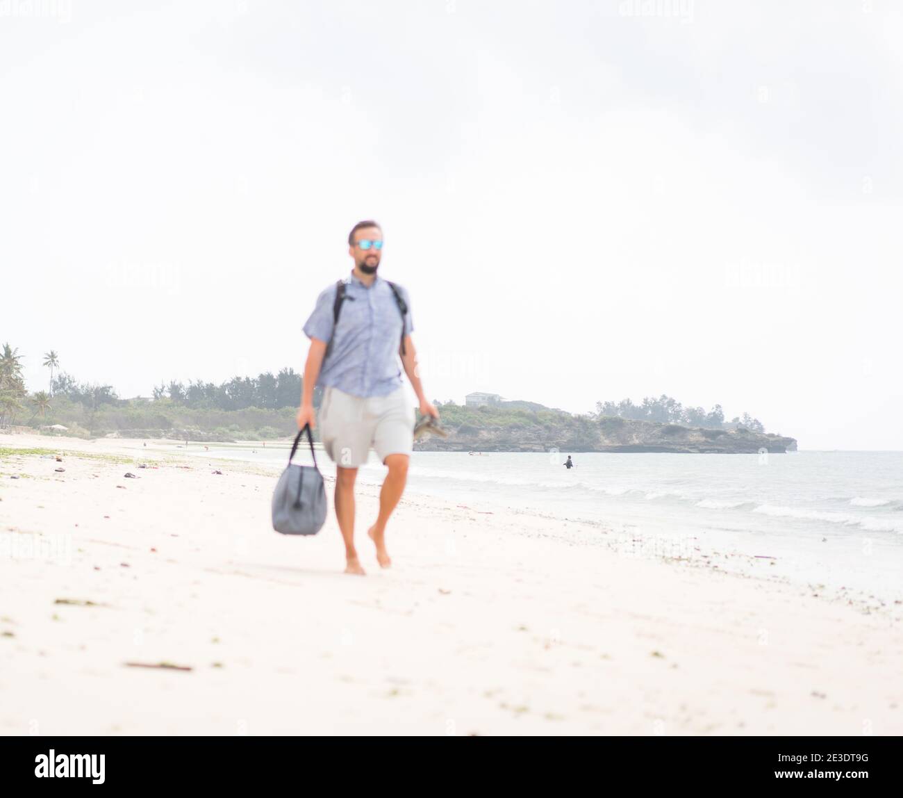 Fröhlicher erwachsener Mann mit Tasche Spaß auf der tropischen Strand Stockfoto