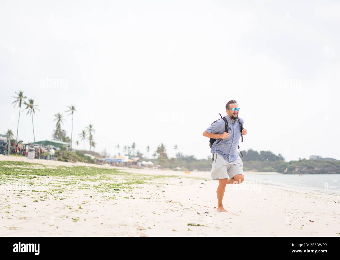 Fröhlicher erwachsener Mann mit Tasche Spaß auf der tropischen Strand Stockfoto
