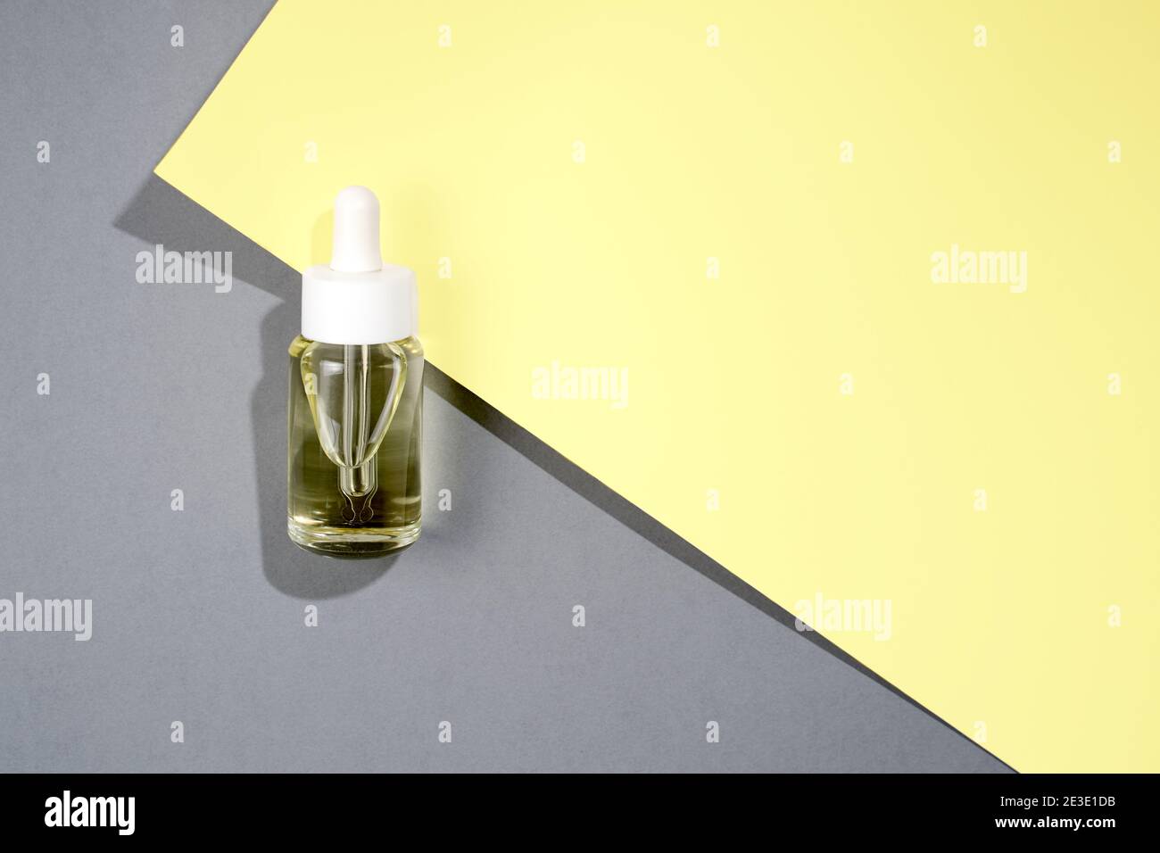 Flach legen kosmetische transparente Flasche mit Öl auf grau und Gelber Hintergrund Stockfoto