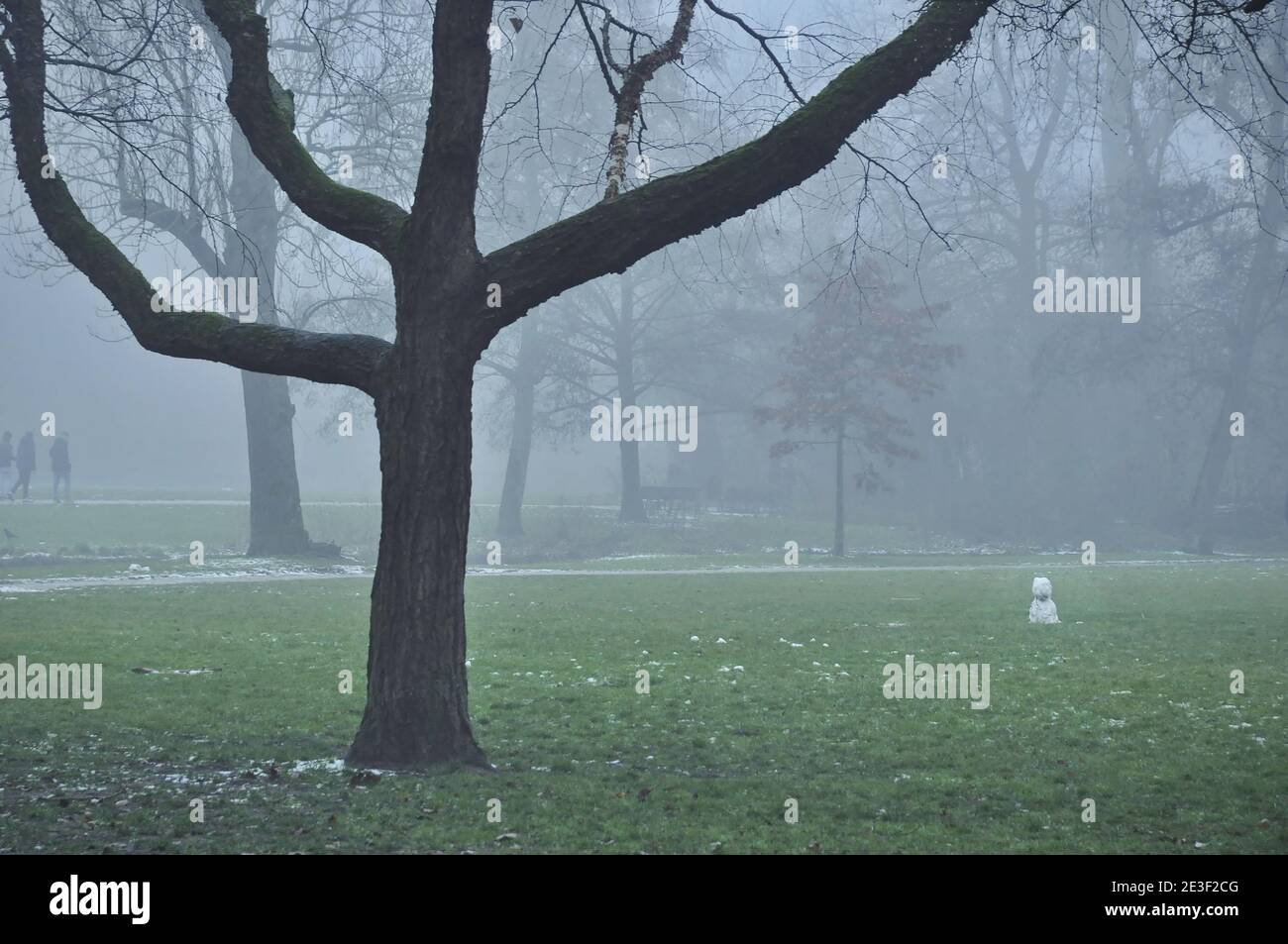 Blick auf den Vondelpark im Winternebel. Ein kleiner, schmelzender Schneemann ist auf der rechten Seite des Bildes, zwischen den kahlen Bäumen. Stockfoto