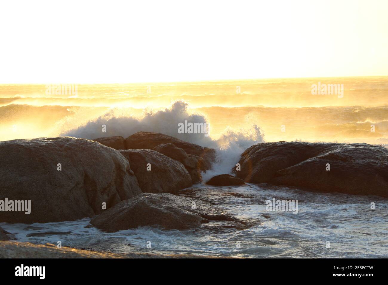 Wellenbrechung auf den großen Felsbrocken der Küste von Camps Bay in Kapstadt, Südafrika Stockfoto