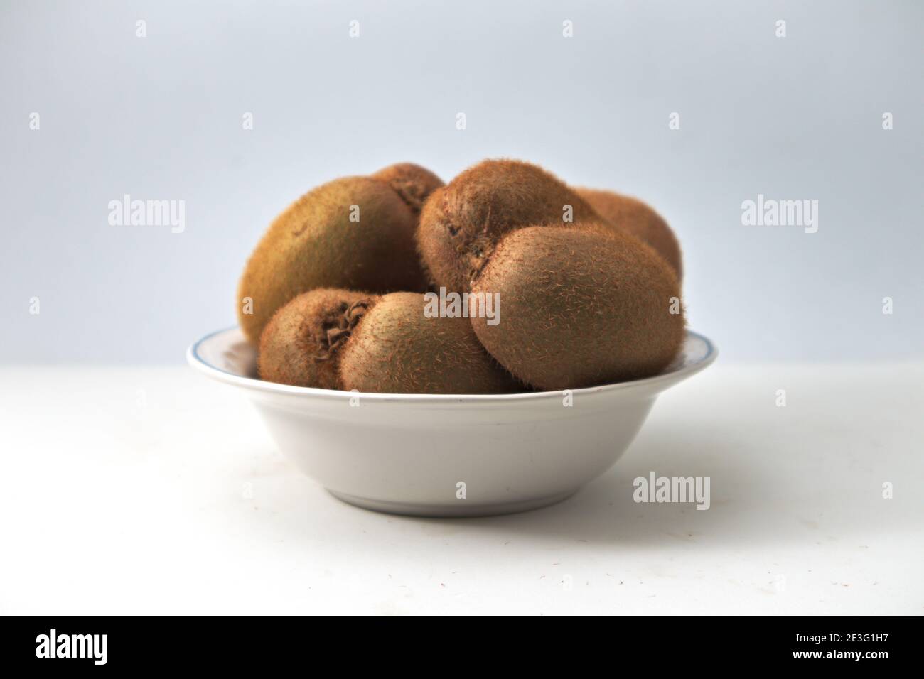 Schüssel mit einigen ungeschälten Stücken Kiwi der Wohnung Geben Sie Text mit neutralem Hintergrund und mit Kopierraum ein Stockfoto