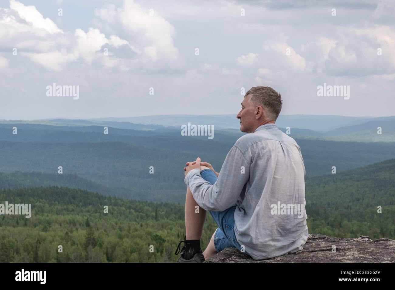 Ein freier Mann mittleren Alters, der eine wunderschöne Aussicht auf das Bergtal genießt. Gesunder Lebensstil und Reisekonzept. Einsamkeit, Einheit mit der Natur. Speicherplatz kopieren Stockfoto